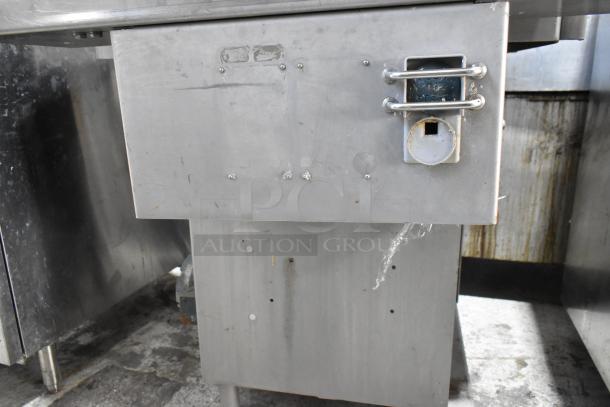 Metal commercial floor-style meat saw, used condition, stainless steel, visible wear and scratches, industrial use.