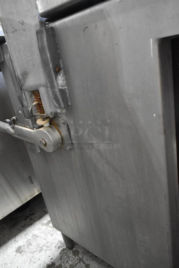 Metal commercial floor style meat saw with sturdy construction. Visible spring mechanism and locking lever. Condition: used.