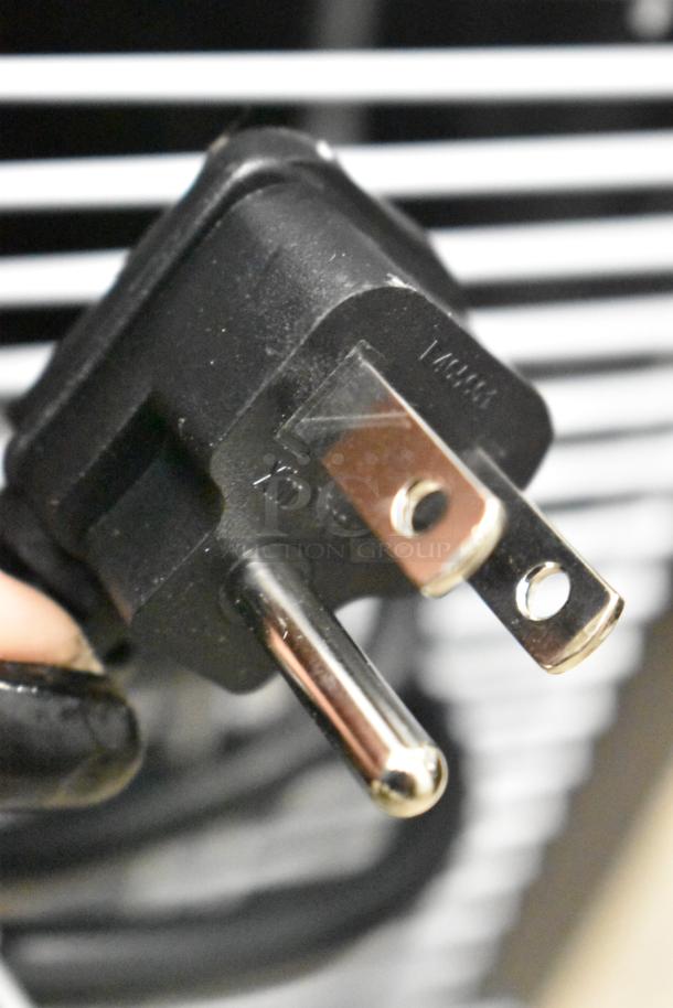 Close-up of a power plug for the KoolMore KM-MDR-1GD-10C commercial cooler, showing metal prongs and plastic housing.