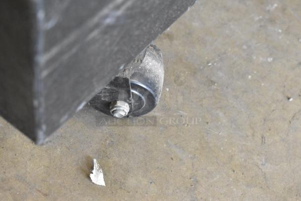 Close-up of a caster wheel on the True GDM-45 commercial cooler, showing minor wear on the floor.