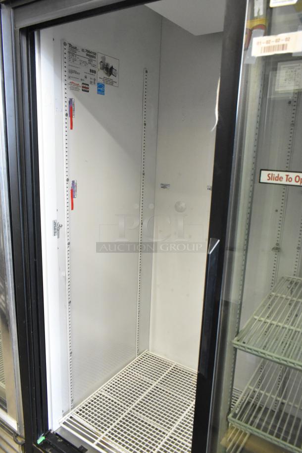 True GDM-45 metal commercial 2-door reach-in cooler, interior view, with poly-coated racks and commercial casters.
