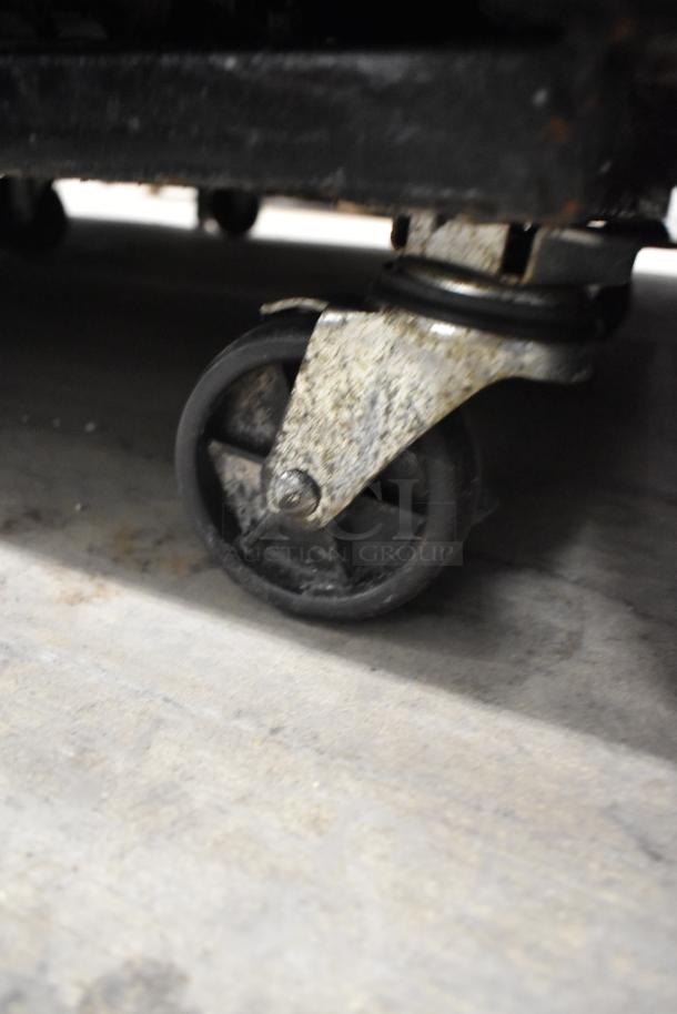 True GDM-33 cooler caster, showing metal wheel and frame. Signs of wear visible, commercial-grade, aiding mobility.