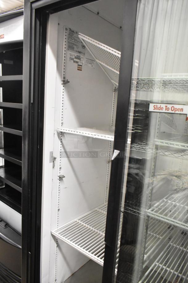 True GDM-33 commercial cooler merchandiser with two glass doors, poly-coated racks, and commercial casters. Model details visible inside.