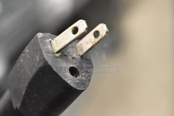 Close-up of a metal prong plug from a Win-holt commercial heated holding cabinet. Details of cabinet not visible.