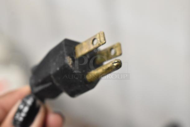 A close-up of a yellowed electrical plug with visible wear on the prongs.