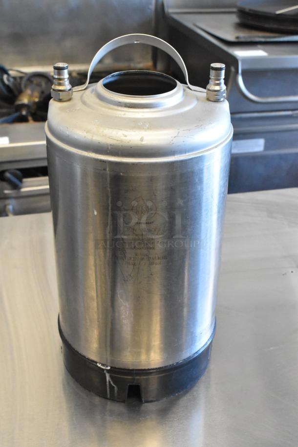 Metal home brew keg with handles and two connectors, showing wear. Marked with capacity and pressure info. Three kegs total.