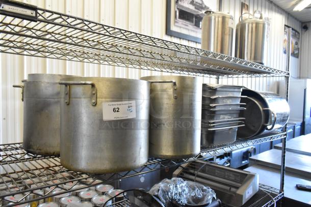 Tiered lot of metal stock pots and stainless steel drop-in bins on wire shelving, label "62" indicates auction lot.