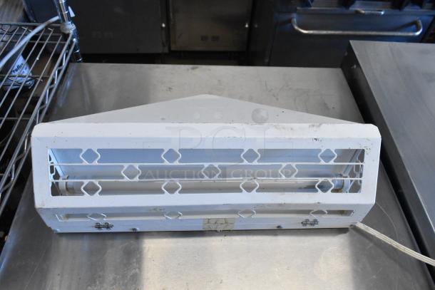 White bug zapper on metal surface, rectangular design with protective grill and visible fluorescent tube, slight wear.