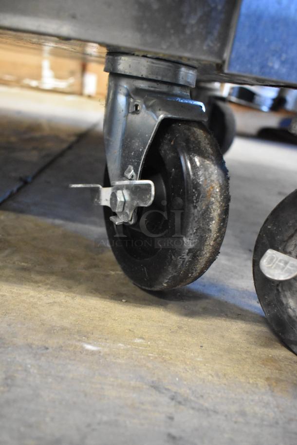 Close-up of sturdy commercial caster of Victory VR-SA-1D-HG V Series cooler, showing metal frame and durable rubber wheel.