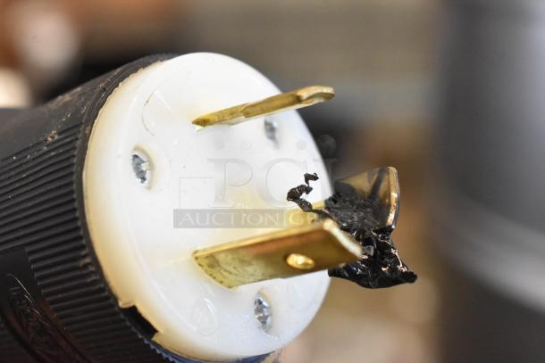 Close-up of a power plug showing a Taylor 337-27 soft serve ice cream machine connector, highlighting its prongs and blackened detail.