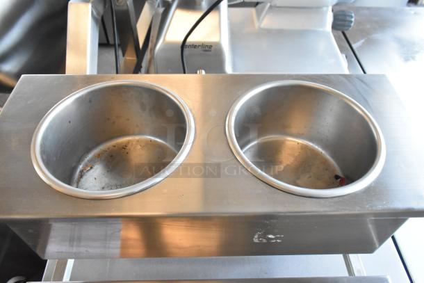 Stainless steel countertop stand with two wells, shows minor wear, suitable for commercial food service.