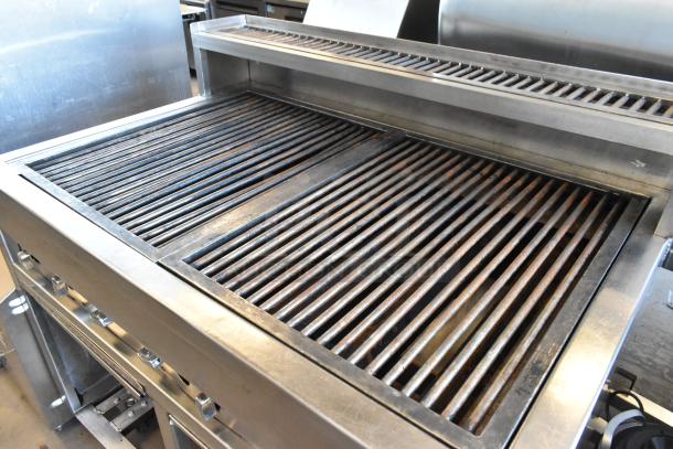 Stainless steel commercial charbroiler grill on casters, used condition, features dual grilling sections and a vented back shelf.