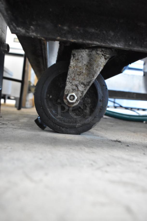 Stainless steel commercial charbroiler grill, features robust caster wheel for mobility, shown in used condition.