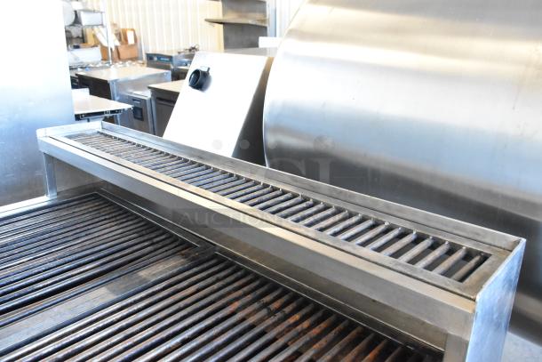 Stainless steel commercial charbroiler grill with adjustable grates, in excellent condition, featuring sturdy commercial casters.