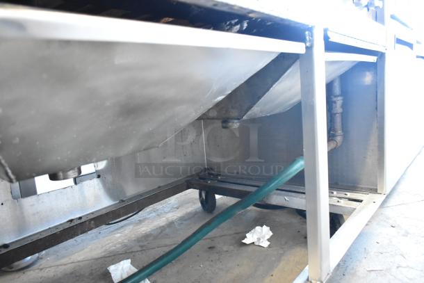 Stainless steel commercial charbroiler grill on casters, underside view, showing drainage connections and condition details.