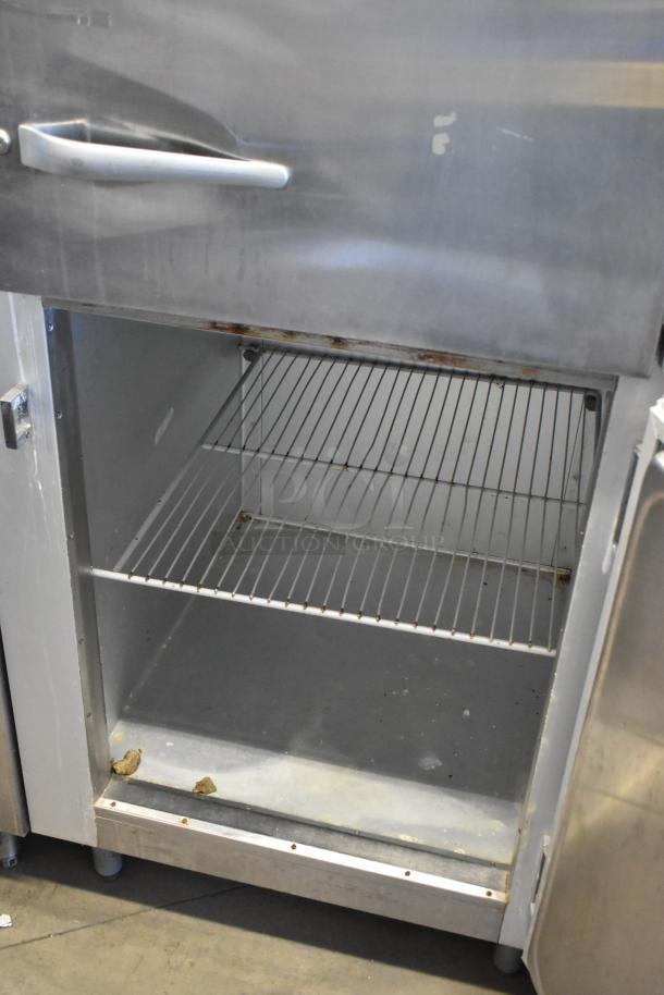Traulsen G12000 stainless steel commercial 2 half-size door reach-in freezer with metal racks, showing slight wear.
