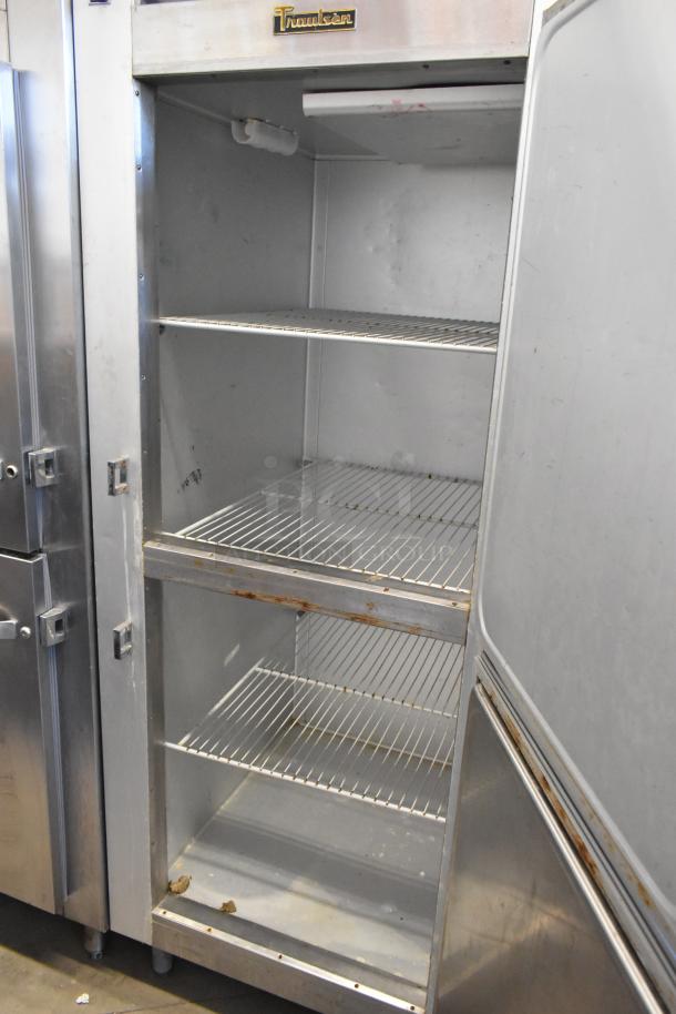 Traulsen G12000 stainless steel commercial freezer, 2 half-size doors, with metal racks, 115 volts, visible wear.