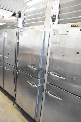 Traulsen RHT132WREHHS stainless steel reach-in cooler with two half-size doors and metal racks, in good condition.