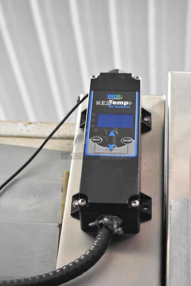 KE2Temp defrost controller on commercial cooler, featuring digital display and control buttons for temperature management.