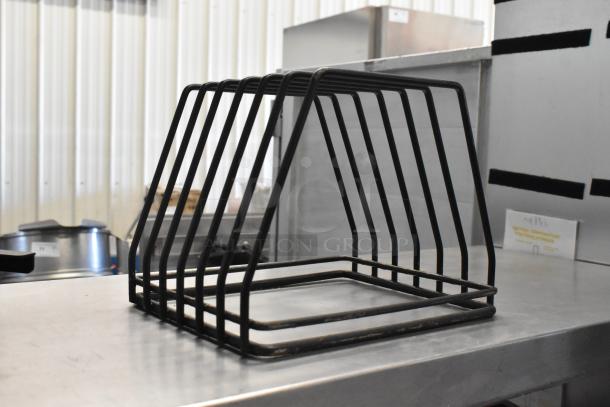 Metal cutting board drying rack with sturdy black frame on metal surface, suitable for kitchen use.
