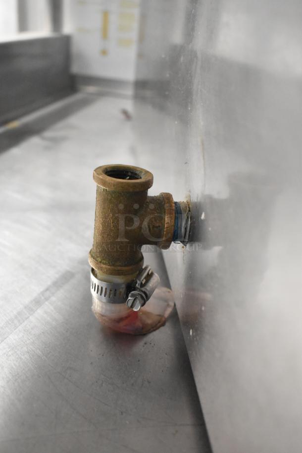 Alt text: Close-up of a metal fitting with a clamp attached to a steel surface in an industrial setting.