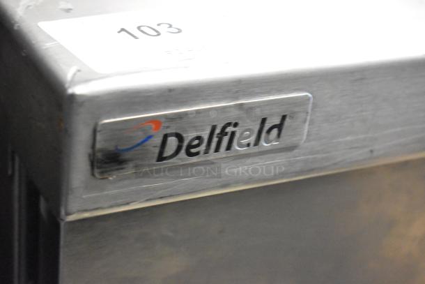 Delfield stainless steel 3-door work top cooler with over shelf, shown with visible brand logo. 115 volts, 1 phase.