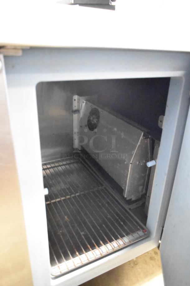 Delfield stainless steel 3-door work top cooler with over shelf, 115 volts, 1 phase, showing interior shelving and fan.