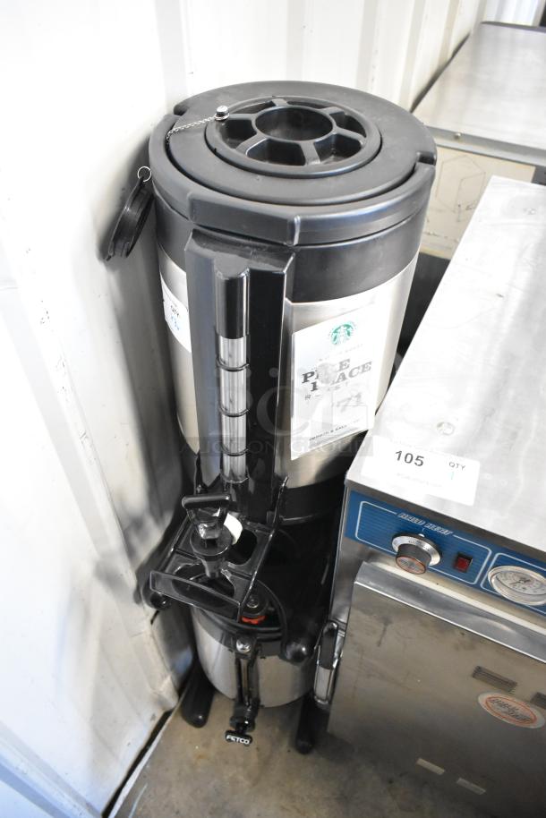 Stainless steel beverage holder dispenser with black lid and tap, featuring a "Pike Place" coffee label.