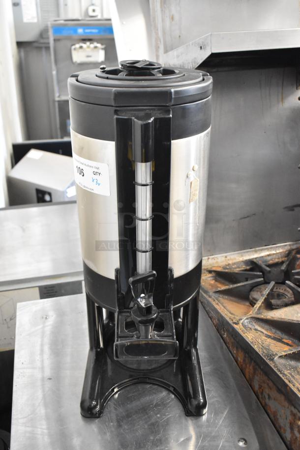 3 stainless steel beverage dispensers with black lids and bases, front spout, auction label "106 QTY. x3." Slight wear visible.