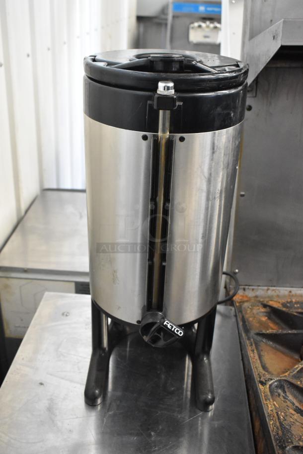 Stainless steel beverage dispenser by Fetco, featuring sleek design and sturdy legs, suitable for catering use.