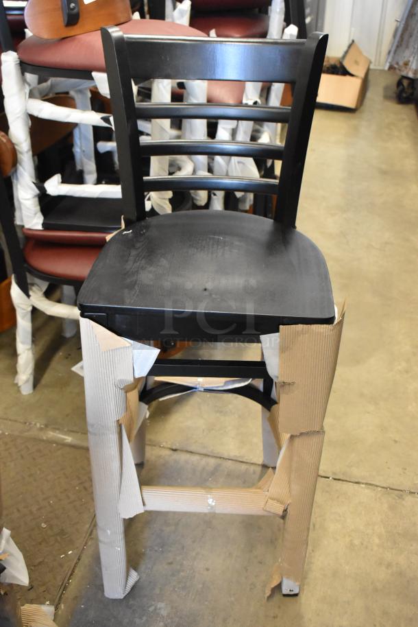 Black bar height chair with ladder back by Lancaster Table & Seating, new condition, protective wrapping visible.