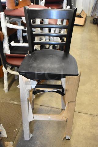 Black bar height chair with ladder back by Lancaster Table & Seating, new condition, protective wrapping visible.
