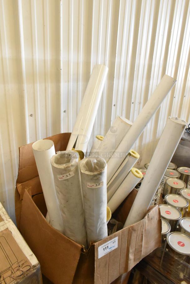 Cardboard box containing 20 various white tubes of different lengths, labeled with measurements.