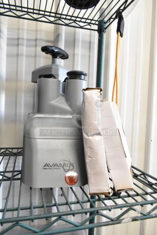 AvaMix food processor attachments on shelf, including continuous feed head, grating blade, and slicing blade.