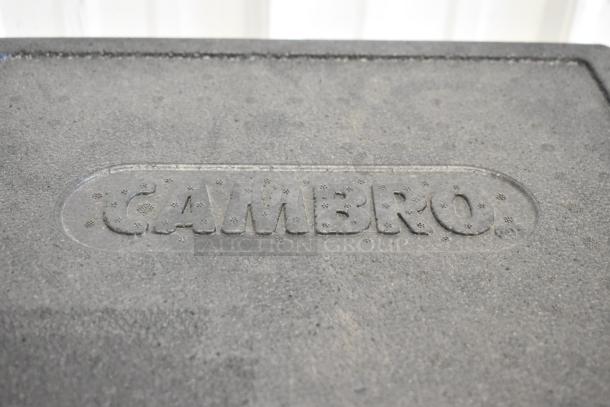 Cambro black insulated portable cooler, textured surface, embossed brand logo on lid, durable and ideal for transport.