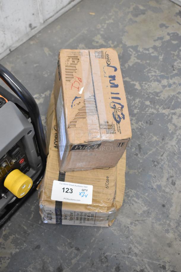 Two unopened boxes labeled with "Purell" and "Acopa" containing a Purell Healthy Soap Dispenser and Acopa Porcelain Plates.