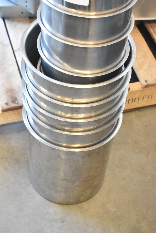 Stack of 10 stainless steel cylindrical drop-in bins, in good condition, showing smooth metal surface and uniform design.