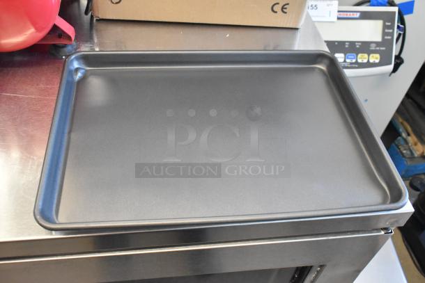 Nordic Ware Naturals scratch and dent aluminum sheet pan with wire in rim, displayed on a metal surface.