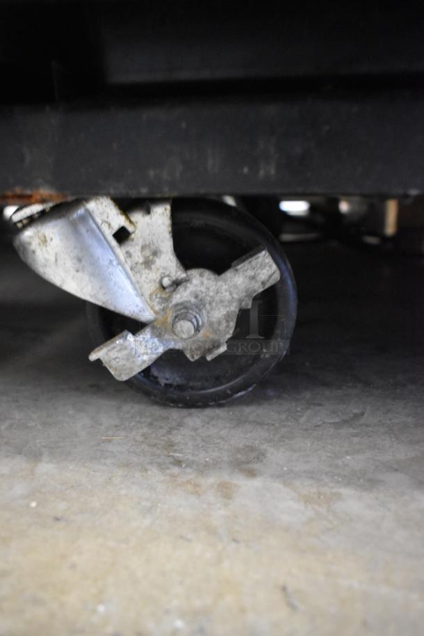 Close-up of a commercial caster wheel from the 2019 True GDM-33-HC-LD cooler, showing metal construction and used condition.