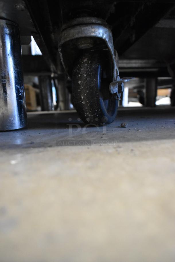 Dirty caster wheel of a True T-23F stainless steel commercial reach-in freezer.