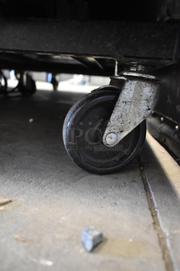 Close-up of a caster wheel from a 2019 True T-23F-HC stainless steel commercial freezer, showing its poly-coated rack and durable caster.