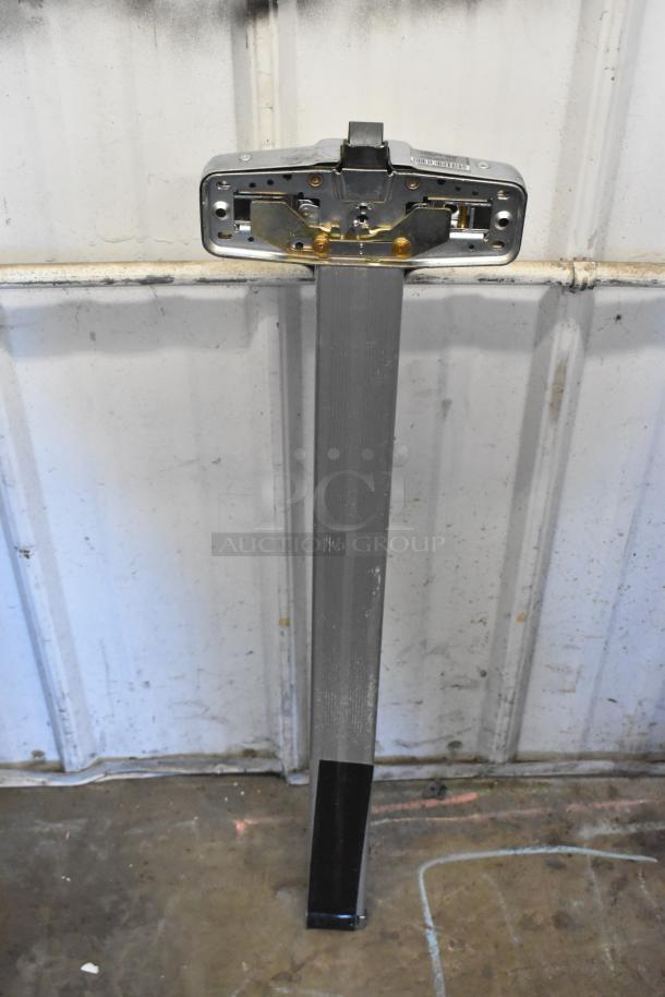 Steel door push bar with exposed mounting mechanism, showing signs of use. Ideal for industrial or commercial settings.