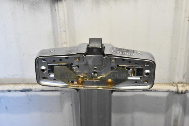 Metal door push bar with mounting plate, visible UL certification label, used condition, suitable for emergency exits.