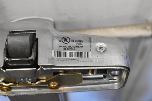 Door push bar with UL listing, labeled "Panic Hardware 99 Series," in used condition. Barcode and model 971235-00 visible.