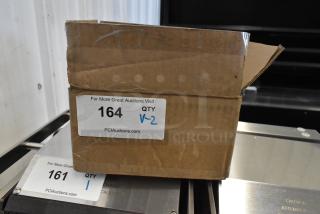 Cardboard box containing two coarse cleaning brushes, labeled "164 QTY V-2" from PCIAuctions.com. Box shows mild wear.