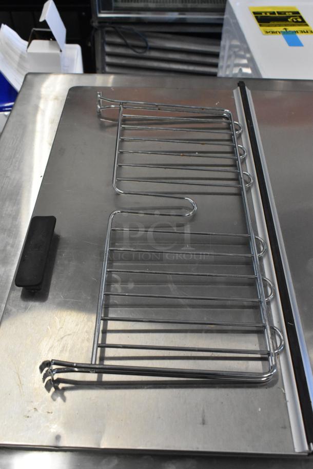 Metal rack on a stainless steel surface, featuring parallel rods and curved edges, in good condition.