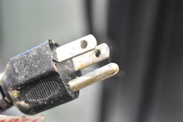 A close-up of a worn, three-prong electrical plug, part of a Thunder Group SEJ-20000 Stainless Steel Rice Cooker, 115 Volts, 1 Phase.