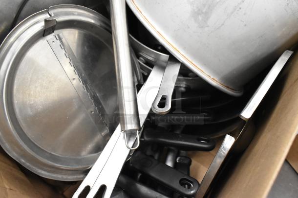 Lot of kitchen items including metal sauce pots, stainless steel utensils, and pot lids in used condition.
