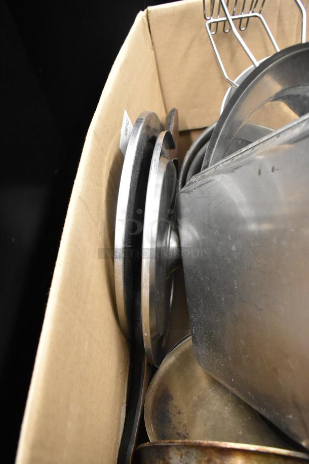 Box with various kitchen items including sauce pots and utensils, some showing signs of use, no visible brands or markings.