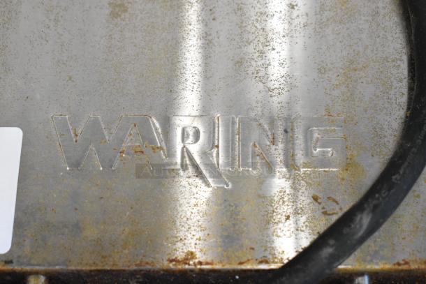 Waring WPG250B stainless steel panini press, visible wear, branded "WARING"; 208 volts, 1 phase, commercial-grade.